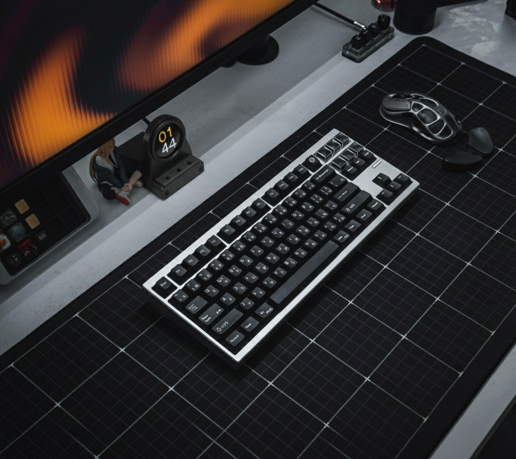 Black keyboard on a desk with a DeskOrbie and mouse in the background